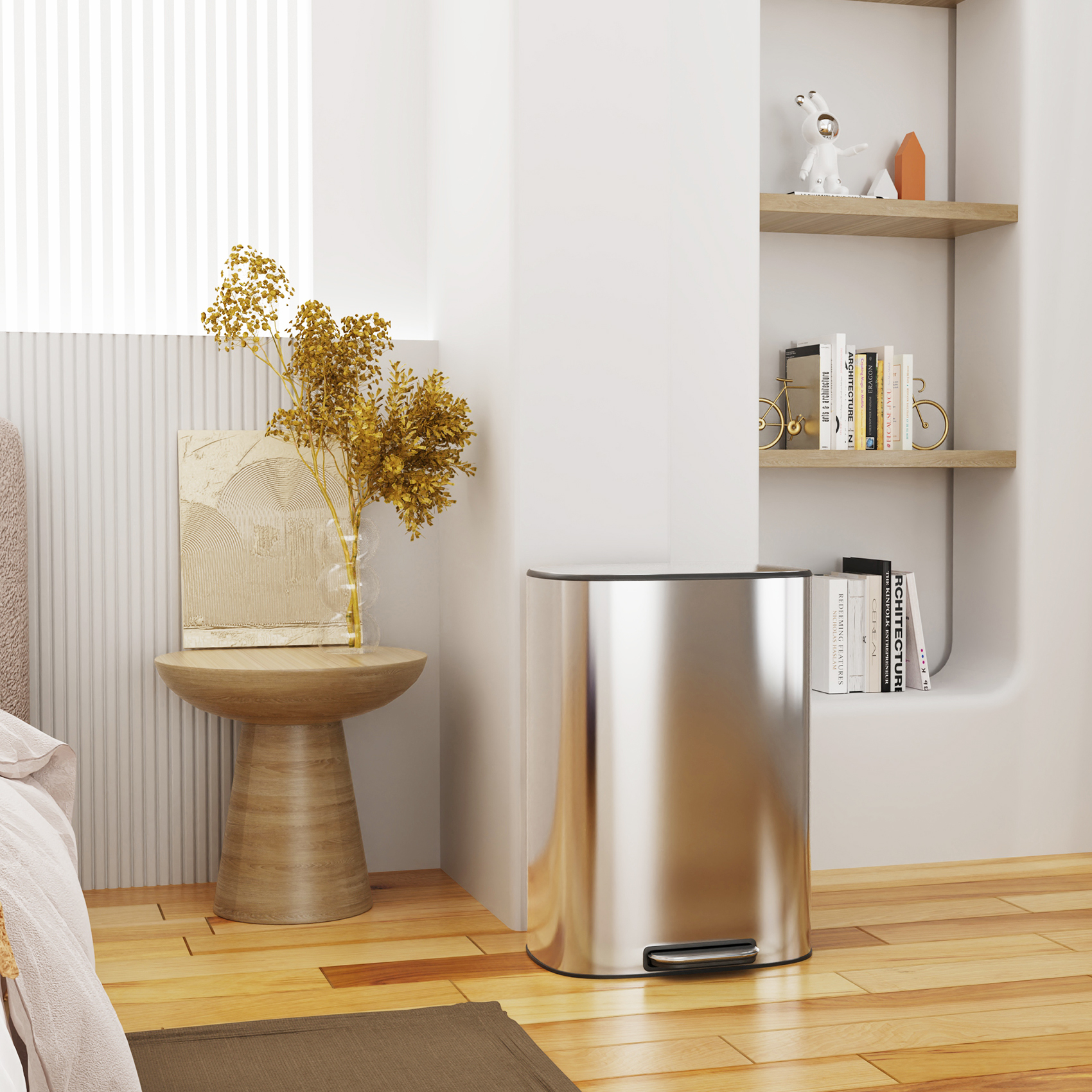 A modern living room corner showcases a 13 Gallon Kitchen Foot Pedal Operated Soft Close Trash Can in fingerprint-proof stainless steel, complemented by a wooden side table adorned with dried flowers and decor. A bookshelf proudly displays books alongside a bear sculpture. Light wood flooring and neutral tones contribute to the cozy atmosphere.